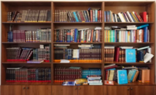 Defocused image. Multi-colored books on the bookshelf in the library. The bokeh effect