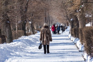 Yaşlı bir kadın parkta yürüyor. Kış günü.