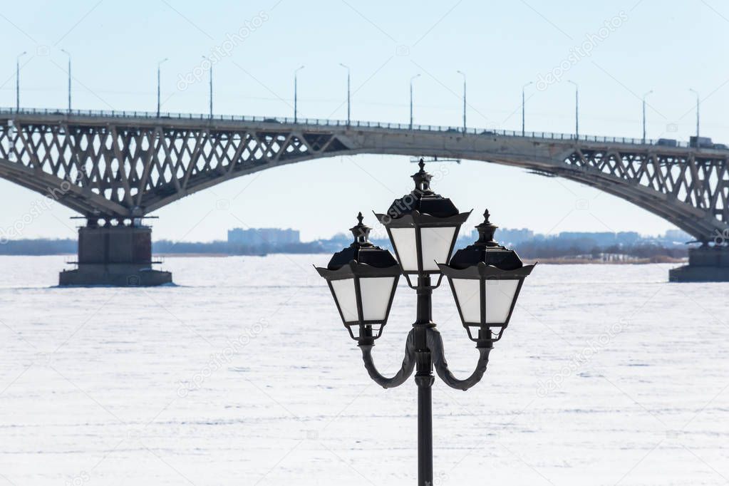 Road bridge across the Volga river between the cities of Saratov and Engels, Russia. Embankment, winter or spring day. Ice on the river.