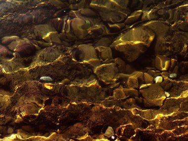 Su dalgaları dalgalanır su altında parlayan kayalar