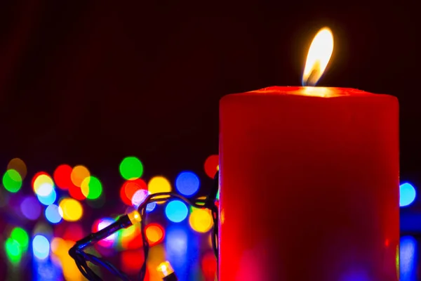 Свеча с рождественскими огнями на заднем плане — стоковое фото