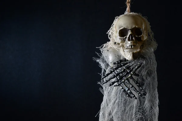 Esqueleto terrível pendurado em um fundo azul escuro . — Fotografia de Stock