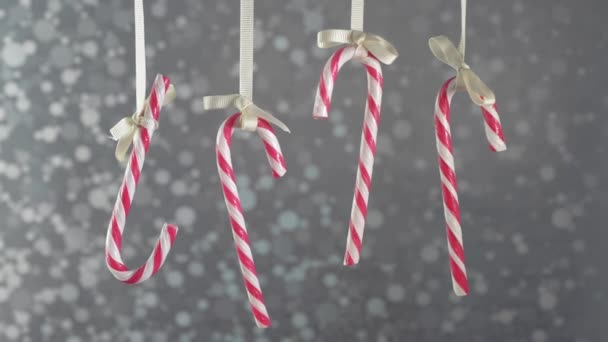 Bastones de caramelo colgando de una cinta en un fondo de plata bokeh . — Vídeos de Stock