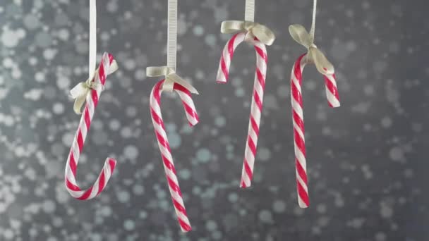 Bastones de caramelo colgando de una cinta en un fondo de plata bokeh . — Vídeos de Stock