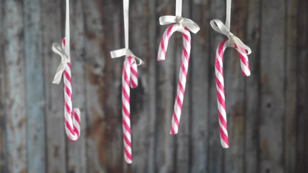 Candy Canes hanging on a ribbon a wooden background. — Stock Video