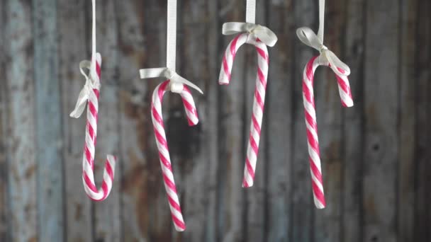 Candy Canes hanging on a ribbon a wooden background. — Stock Video