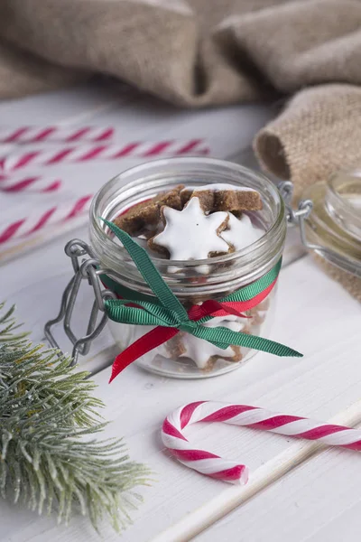 Karácsonyi cookie-k és édességet vesszők, egy fehér fából készült asztal üveg edény. — Stock Fotó
