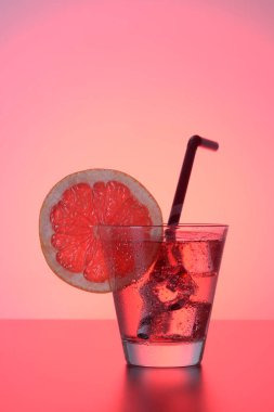 Greyfurt, buz ve kırmızı bir arka plan üzerinde çizgili içme saman ile taze kokteyl.