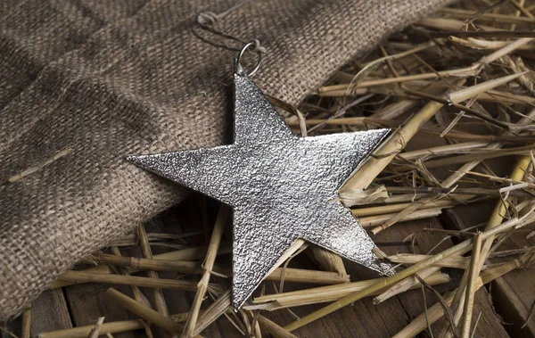 Karácsonyi csillag egy zsákvászon fém háttér és a széna. — Stock Fotó