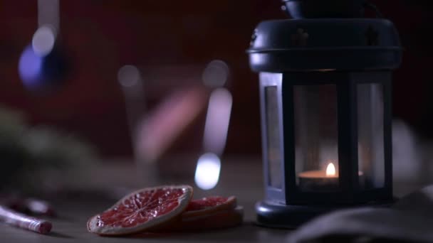 Cocktail Grapefruit, kaars, tak van de zilverspar met Kerstmis speelgoed en snoep stokken op een rode baksteen — Stockvideo