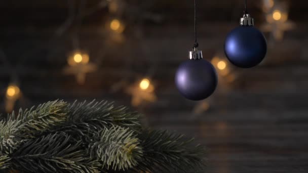 Two blue Christmas ball and spruce branches on the background of beautiful bokeh. — Stock Video