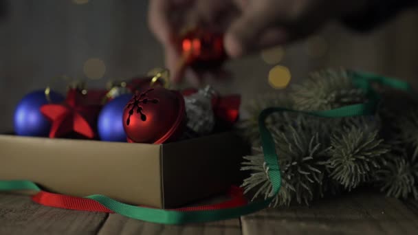 Una caja de decoraciones navideñas sobre una vieja mesa de madera . — Vídeo de stock