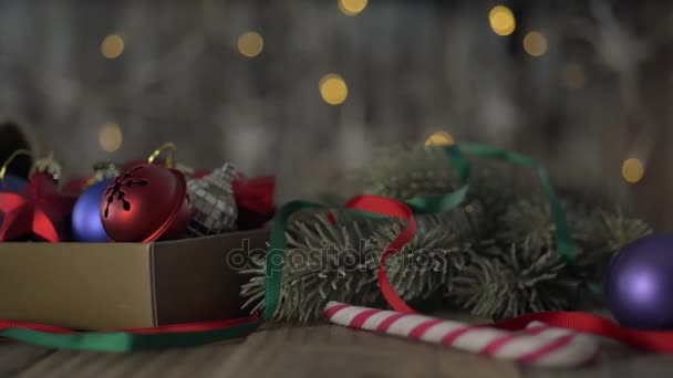 Una caja de decoraciones navideñas sobre una vieja mesa de madera . — Vídeo de stock