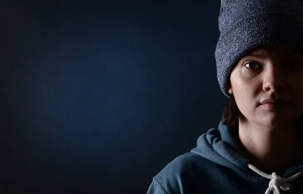Giovane ragazza in un berretto a maglia su uno sfondo scuro . — Foto Stock