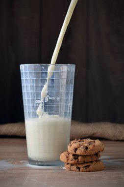 Bir bardak süt ve koyu arka plan üzerinde çikolata parçaları ile tanımlama.