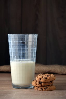 Bir bardak süt ve koyu arka plan üzerinde çikolata parçaları ile tanımlama.