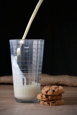 Bir bardak süt ve koyu arka plan üzerinde çikolata parçaları ile tanımlama.