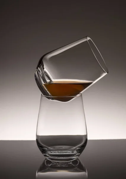 Una torre de dos vasos transparentes con whisky sobre un fondo oscurecido . — Foto de Stock