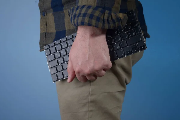 Homme avec clavier dans les mains sur un fond bleu . — Photo