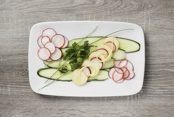 Sommersalat mit Gurken, Radieschen, Kohlrabi mit Petersilie auf weißem länglichem Teller. — Stockfoto