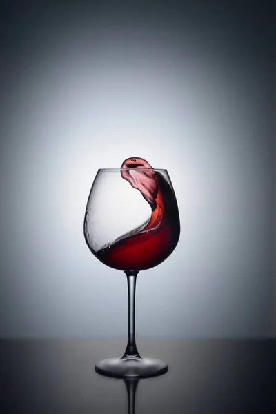 Splash of red wine in a glass on a white background with reflection — Stock Photo, Image