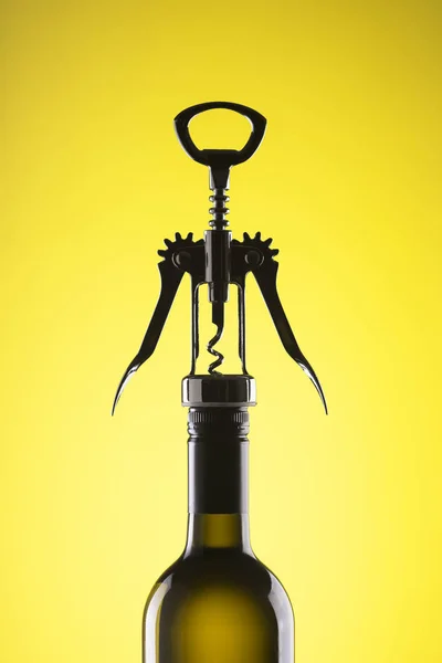 Una botella de vino con un sacacorchos elegante para abrir sobre un fondo amarillo . — Foto de Stock