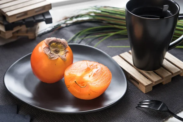 Reife Persimmons Auf Einem Schwarzen Teller Stockfoto