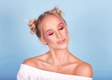 Parlak, alışılagelmedik makyajlı ve iki külahlı, çok tatlı tatlı şeker kız zıplayan, eğlenen ve gülen kız. Bu mavi arka planda bir bayan. Yanında büyük turtalar ve çörekler var. Makaronların portresi.