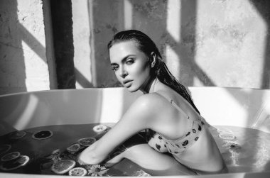 Banyodaki seksi su meyveli mayo, banyo yapan seksi esmer gözler, güneşli arka plan, baştan çıkarıcı bir şekilde ıslak göğüs gölgeleri, portakallar, pembe sıçramalar, fotoğraf stüdyosu modeli göz kamaştırıcı saçlar.