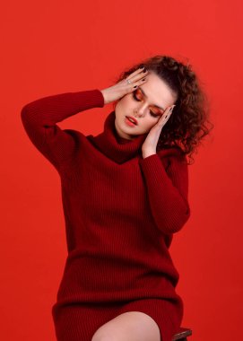 Kırmızı elbiseli güzel bir kız ve parlak kırmızı Smokey makyajlı ve bulanık oklu ben. Kırmızı arka planda bir portre, tamamen kırmızı, gülen ve eğlenen bir kız, Afro kıvırcık saçları ve harika bir atletik figürü var.