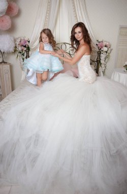 Mutlu anne ve kız güzel elbiseler içinde gerçek prensesler çiçeklerle çevrili baharın gelmesiyle sevinirler.