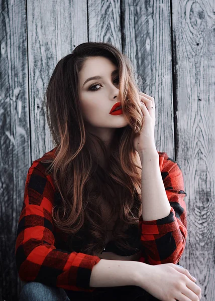 Kırmızı dudaklı, tişörtlü ve gri arka planda kot pantolonlu güzel bir Rus kız.