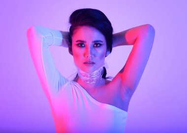 Parlak esmer Asyalı kız neon ışıklı pembe ve mor renkli şık elbiseli.