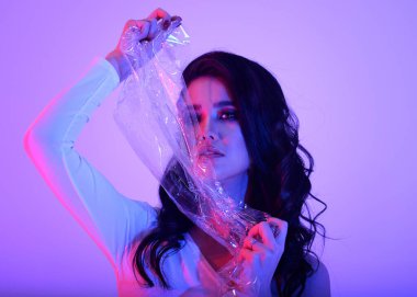 Parlak esmer Asyalı kız neon ışıklı pembe ve mor renkli şık elbiseli.