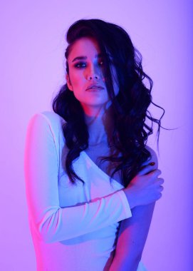 Parlak esmer Asyalı kız neon ışıklı pembe ve mor renkli şık elbiseli.