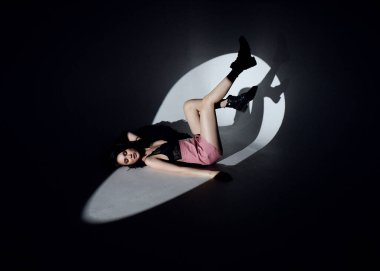 Parlak esmer Asyalı kız farklı arka planda ve gösterişli elbiseli bir projektörü var.