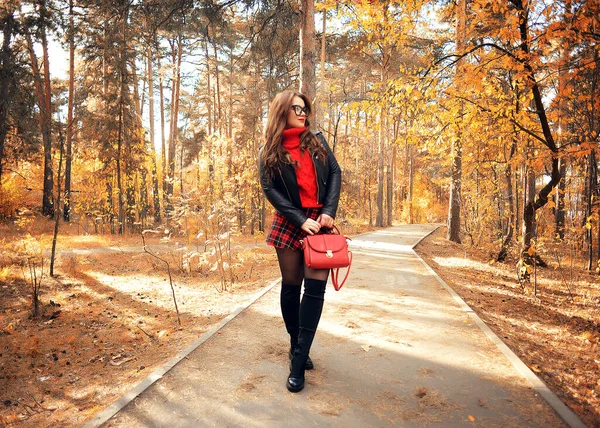 一个穿着红色毛衣 眼镜和苏格兰裙的漂亮姑娘穿过秋天的公园 尽情享受生活 — 图库照片