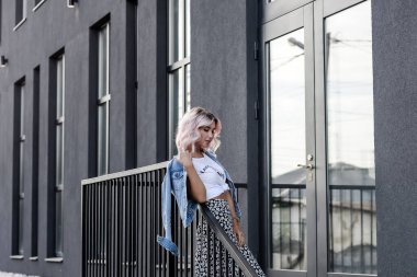 Geometrik bir kara evin arka planına karşı kentsel kıyafet giymiş güzel bir sarışın kız.