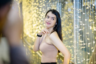 Neşeli bir Asyalı kadın, Noel festivali ve yeni yıl kutlamaları için arka plan süslemeleriyle fotoğraf çekmekten zevk alıyor..