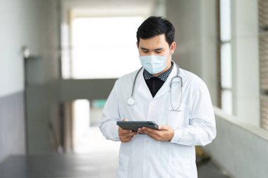 Genç, neşeli ve yakışıklı bir doktorun portresi emin bir şekilde ofisinde duruyor..