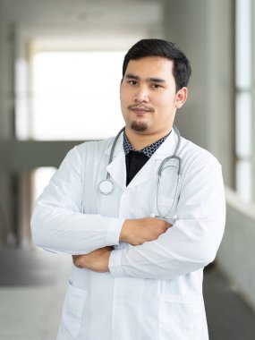 Genç, neşeli ve yakışıklı bir doktorun portresi emin bir şekilde ofisinde duruyor..