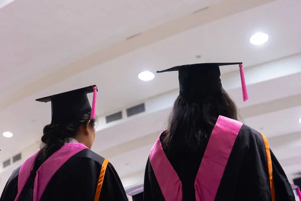 Rearview and soft selective focus of the graduates in the graduation commencement ceremony receiving a diploma degree certificate.