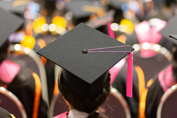 Rearview and soft selective focus of the graduates in the graduation commencement ceremony receiving a diploma degree certificate.