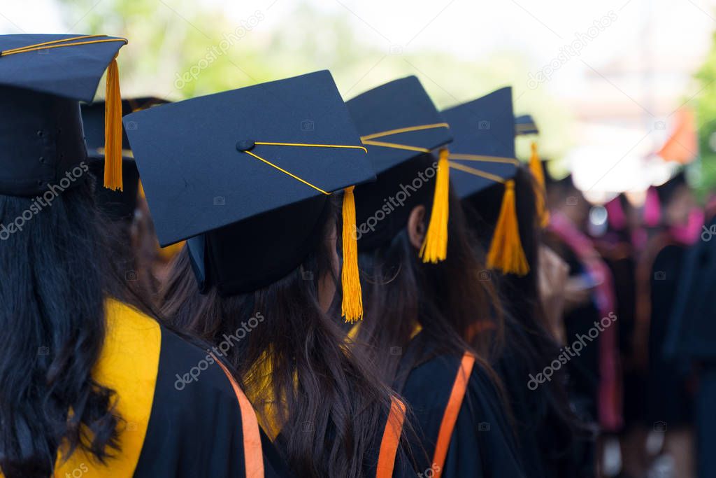 Rearview and soft selective focus of the graduates in the graduation commencement ceremony receiving a diploma degree certificate.