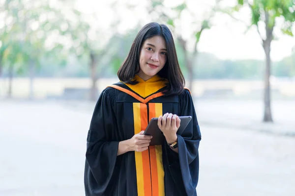 Jovem Alegre Bonito Gradute Feminino Vestindo Vestido Acadêmico Segurando Tablet — Fotografia de Stock