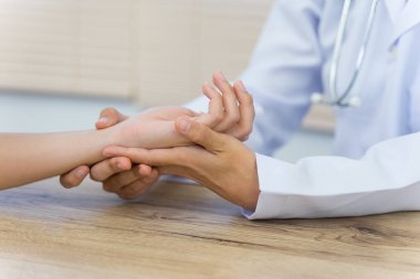 Hastanın ellerini tutarak temel tıbbi muayeneyi ve teşhisi yapan bir doktora yaklaş.