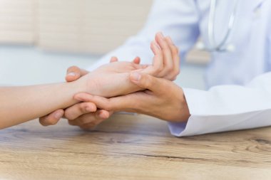 Hastanın ellerini tutarak temel tıbbi muayeneyi ve teşhisi yapan bir doktora yaklaş.