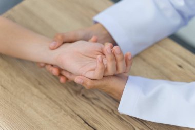 Hastanın ellerini tutarak temel tıbbi muayeneyi ve teşhisi yapan bir doktora yaklaş.