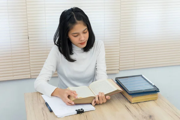 Young cheerful Asian student female university student studying in a self-study room in the university library to do her assignment and prepare for the examination.