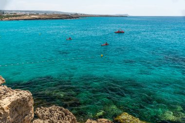 CYPRUS, NISSI BEACH - MAY 12/2018: Tourists swim on catamarans and kayaks in the popular bay of the Mediterranean Sea.